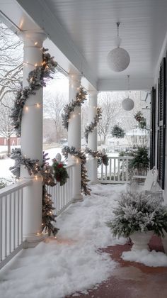 the porch is covered in snow and decorated with christmas garlands, potted plants and lights