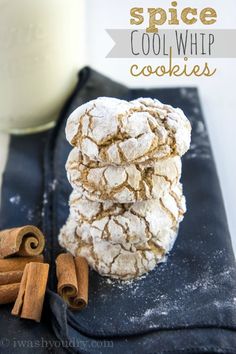 cinnamon sticks and powdered sugar sit on a black tray next to a glass of milk