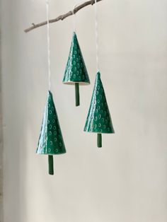 three green plastic christmas trees hanging from a tree branch