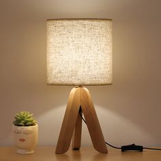 a wooden table with a lamp on it and a potted plant next to it