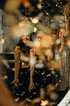 three women standing next to each other with confetti in front of their faces