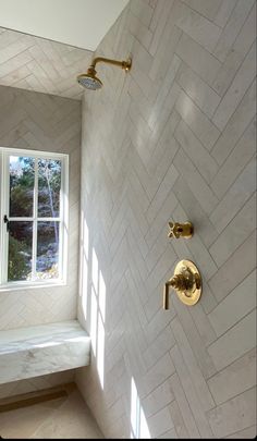 a bathroom with a window, shower head and marble tile wall in it's corner