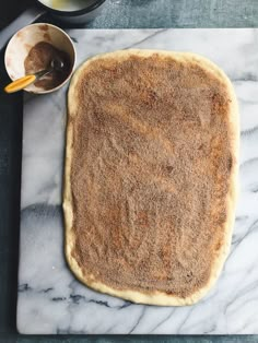 an uncooked pastry sitting on top of a white marble counter next to bowls and utensils