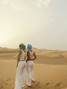 two women are standing in the sand dunes