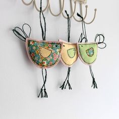 three birds hanging from hooks on a wall