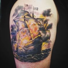 a man's arm with a ship on it and flames coming out of the sails