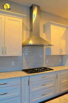 an empty kitchen with white cabinets and stainless steel range top hood over the stovetop