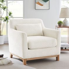 a white chair sitting in a living room next to a painting on the wall and floor