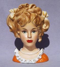 a figurine of a woman with blonde hair and blue eyes wearing an orange dress