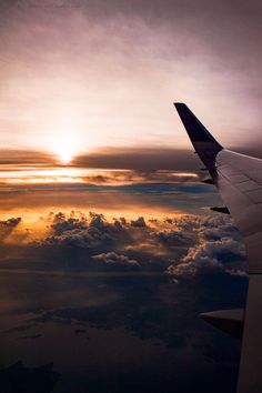 the wing of an airplane as it flies through the sky with clouds in the background