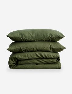 three pillows stacked on top of each other in olive green linens, with the covers folded down