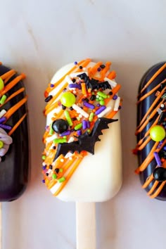 three pops decorated with halloween candy and sprinkles