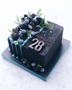 a birthday cake decorated with berries and blueberries is on a white tablecloth that says happy 20th