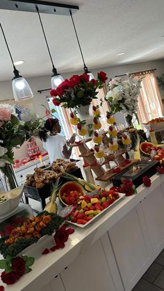 a buffet table filled with lots of different types of food and flowers in vases