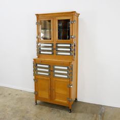 a tall wooden cabinet with metal handles and drawers on it's sides, against a white wall