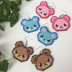 four cross stitch earrings with teddy bears on them and one bear hanging from the back