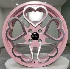 a pink and silver wheel with hearts on the front, sitting on a white pedestal