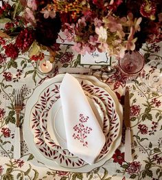 the table is set with red and white plates, silverware, and napkins