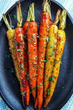 four carrots on a black plate with parsley sprinkled on the top