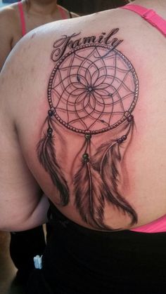 the back of a woman's shoulder with a tattoo on it that says dream catcher