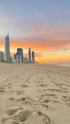 there is a surfboard on the beach with buildings in the background