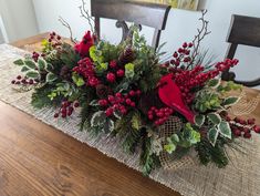 a christmas centerpiece on a table with red berries and greenery