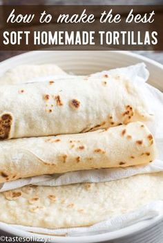 two burritos sitting in a white bowl on top of a wooden table