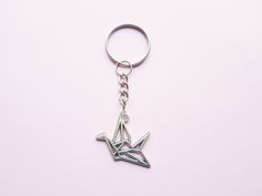 a metal origami bird keychain on a pink background