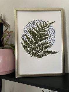 a fern leaf is displayed in a gold frame