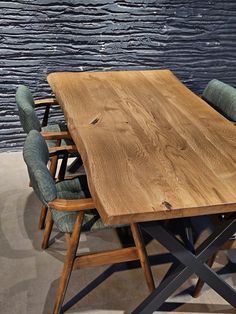 a wooden table with chairs around it in front of a blue wall and stone floor