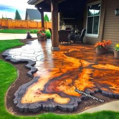 an outdoor patio that has been painted with orange and yellow paint on the concrete, surrounded by green grass