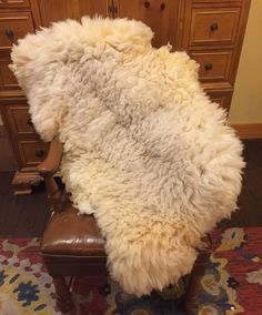 a sheepskin rug sitting on top of a chair in front of a wooden dresser