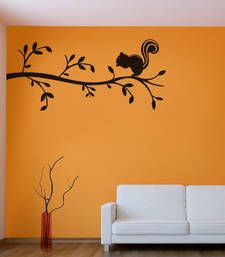 a living room with an orange wall and black squirrel decal on the tree branch