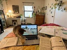 a cat sitting on top of an open book next to a laptop computer and books