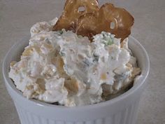 a white bowl filled with potato salad and two pieces of pretzel sticking out of it