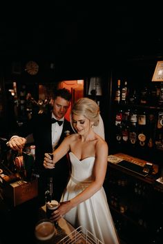 a bride and groom are preparing to drink beer together in the bar at their wedding