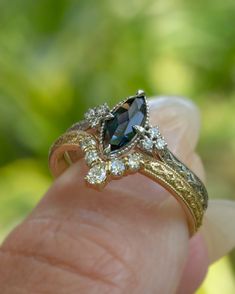 a woman's hand is holding a ring with an oval shaped blue and white diamond