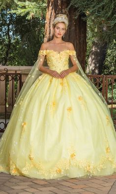 a woman in a yellow dress standing next to a tree wearing a tiara and veil