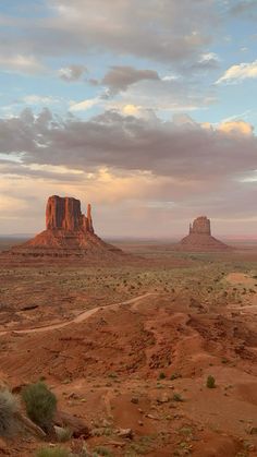 the desert is full of red rocks and green grass, with a large rock formation in the distance