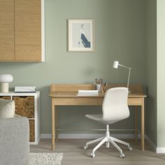 a desk with a chair, lamp and pictures on the wall in a living room