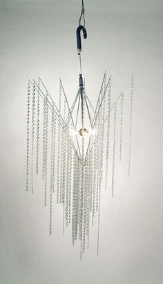 a chandelier hanging from the ceiling in front of a white wall with chains attached to it