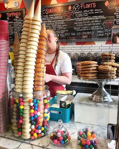 a woman standing in front of a counter filled with lots of donuts and candy