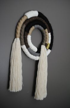 four tassels are hanging on the wall with white and brown fringes around them