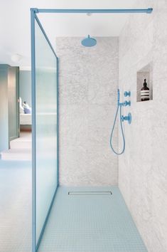 a bathroom with a blue shower head and white tile walls, along with a walk in shower