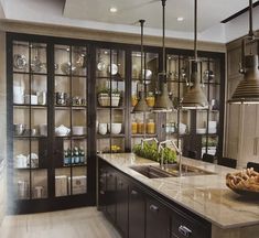 a kitchen filled with lots of counter top space and hanging lights above the island area