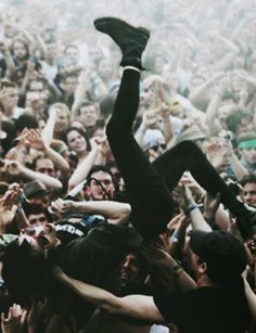 a man is in the middle of a crowd with his arms up and legs spread out