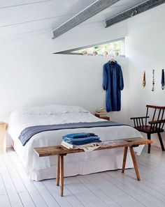 a bed room with a neatly made bed next to a wooden table and two chairs