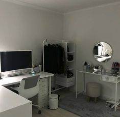 a white desk with a computer monitor and keyboard on top of it next to a mirror