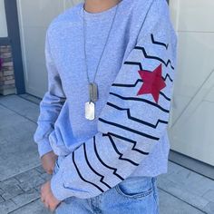 a woman wearing a blue sweatshirt with a red star on the front and silver chain around her neck