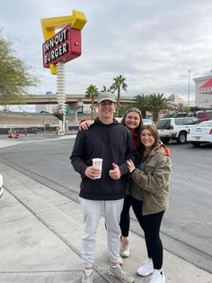 two people standing in front of a dunkin'donuts sign with a coffee cup